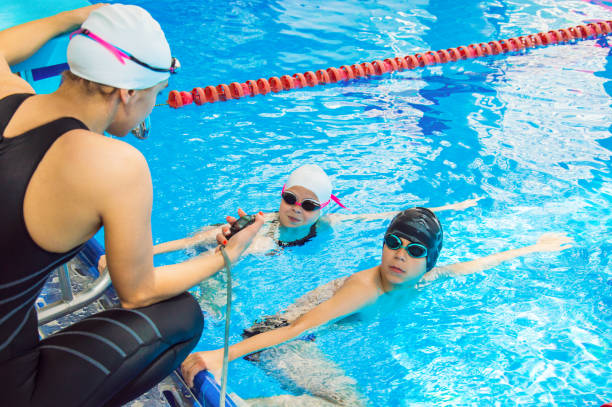 The instructor in the pool with a stopwatch marks the time at the start stock photo