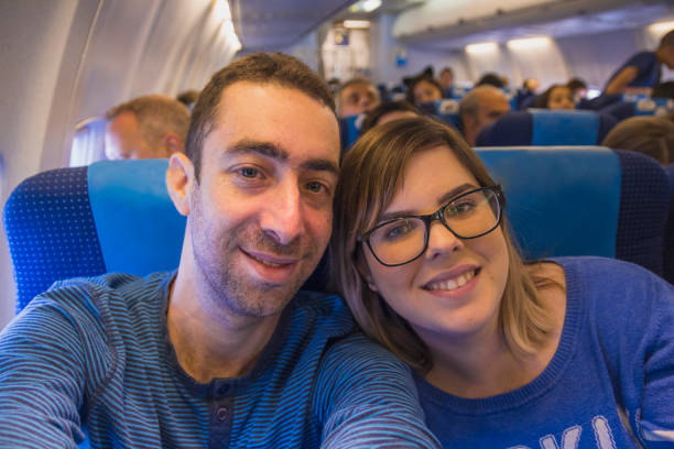 istock Happy couple taking selfie with smartphone or camera inside airplane 801318458