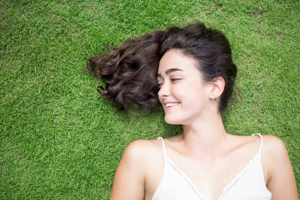 istock Happy young woman lying on lawn looking away 801332834