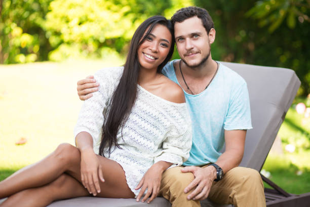 istock Man Embracing Asian Girlfriend on Chaise Longue 801343780