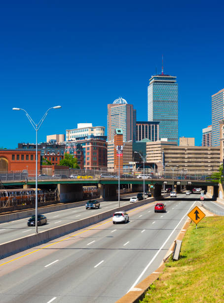Boston, USA: Cityscape of Boston Back Bay against the clear blue sky, view of highway with traffic, Prudential Center and surrounding buildings Boston, Massachusetts - June 2016, USA: Cityscape of Boston Back Bay against the clear blue sky, view of highway with traffic, Prudential Center and surrounding buildings boston prudential building stock pictures, royalty-free photos & images