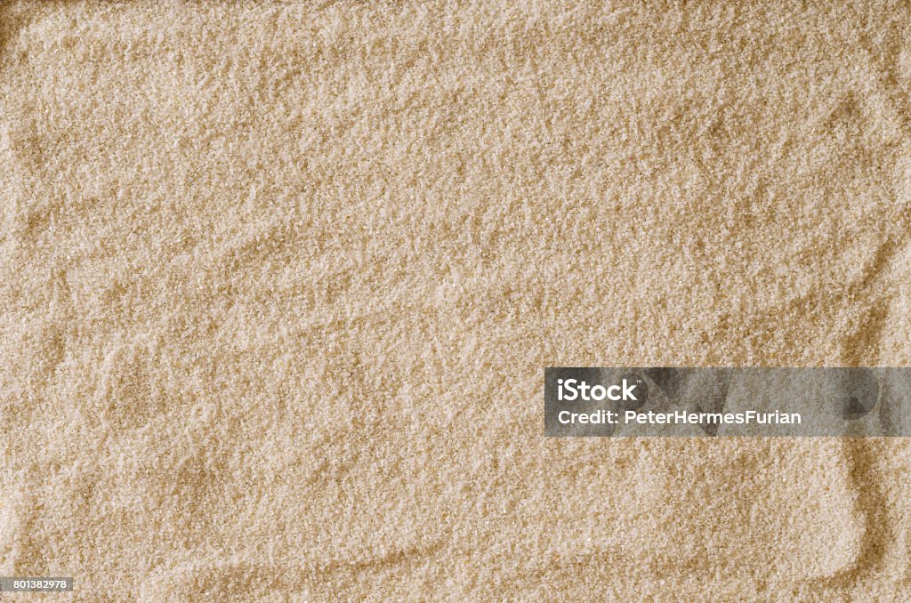 Rough and uneven empty sand surface Rough and uneven empty sand surface to use as a background or texture. Light brown and ocher colored grains of sand. Macro photo close up from above. Abstract Stock Photo