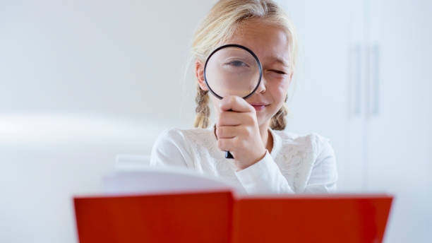 istock Little blond girl looking through a magnifying glass 801386250
