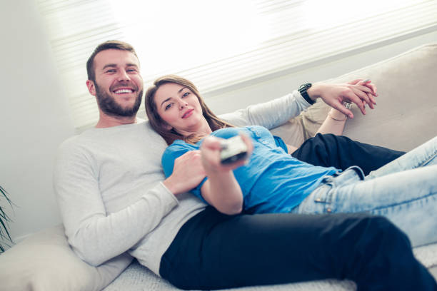 istock Lovely Couple at Home Watching TV and Lying on Sofa 801388836