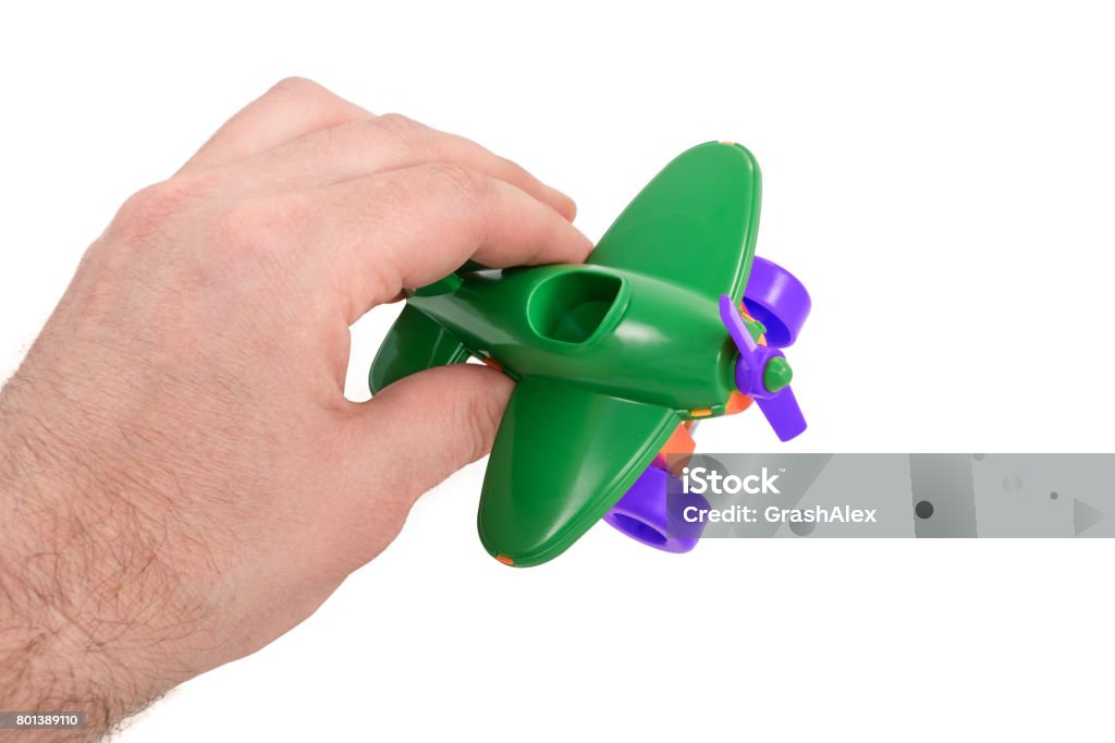 Man hand is played by airplane Man hand holds a toy in his hand - a green children airplane with a propeller, isolated on a white background Adult Stock Photo