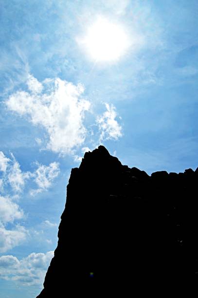 istock Silhouette of a cliff with bright sun and sky in background 801396608