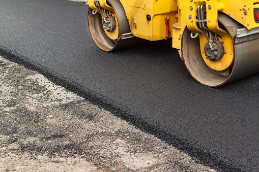 A big vibration  roller compacting asphalt on a new road