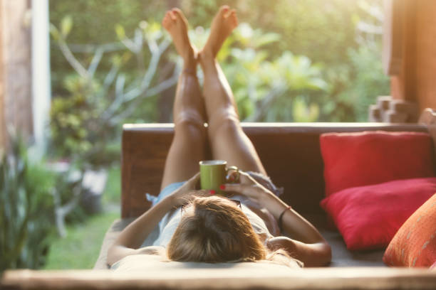 Girl drinking coffee / tea and enjoying the sunrise / sunset in garden. Girl drinking coffee / tea and enjoying the sunrise / sunset in garden. relaxation lying on back women enjoyment stock pictures, royalty-free photos & images