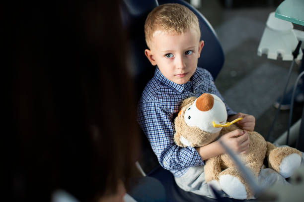 kleiner junge betrachtet man waschen teddybär zähne zahnarzt - human teeth little boys behavior expressing negativity stock-fotos und bilder