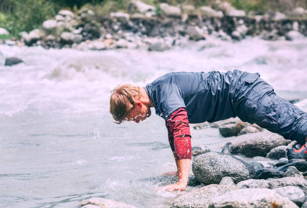istock Traveler man washes his face with cold water in mountain river 801522220