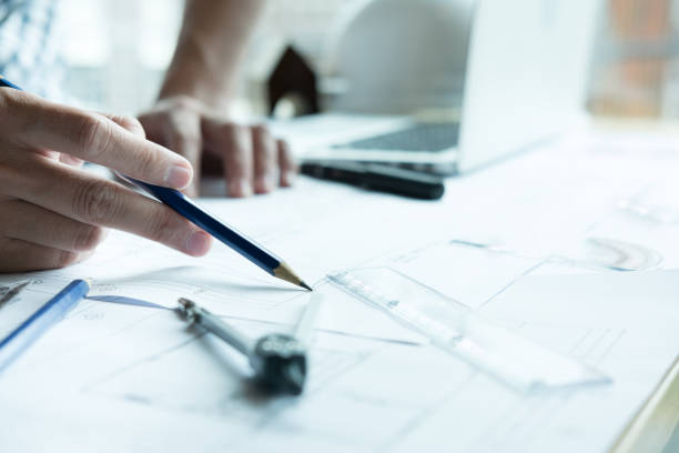 istock Architect working on real estate project at workplace. Male engineer hand working with living house blueprint at office. Business, people, construction and building concept 801525330