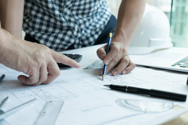 istock Architect working on real estate project with partner at workplace. Male engineer hand discussing with colleague on living house blueprint at office. Business, people, construction and building concept 801525438