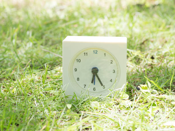 istock White simple clock on lawn yard, 6:25 six twenty five o'clock 801561634