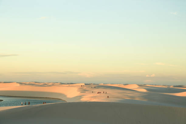 People walking on a sand dunes at sunset, in Lençois, Maranhão, Brasil