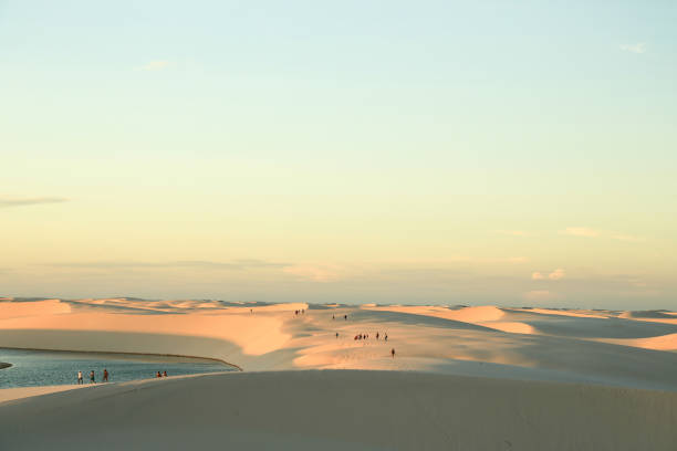 People walking on a sand dunes at sunset stock photo