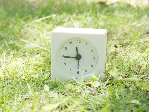 istock White simple clock on lawn yard, 11:45 eleven forty five o'clock 801587284
