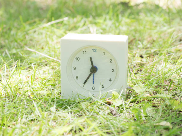 istock White simple clock on lawn yard, 11:35 eleven thirty five o'clock 801587658