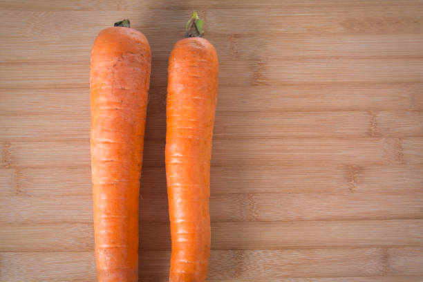 Fresh carrot on a wooden board in kitchen.