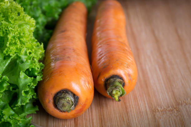 Fresh carrot on a wooden board in kitchen.