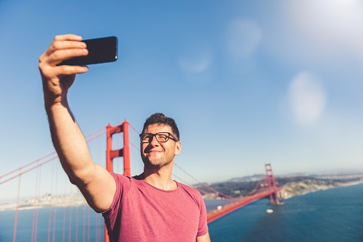 Young man making a selfie with the Golden Gate