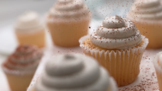 Cinnamon sprinkled onto vanilla cupcakes