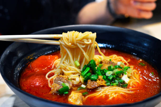 istock Chopsticks Pick Up Chinese Tomato Beef Noodle Soup from A Large Bowl. 801640072