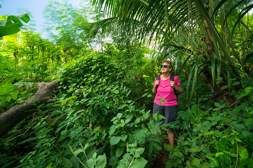 fit 70 yeard old woman during tropical island hike on sunny vacation day
