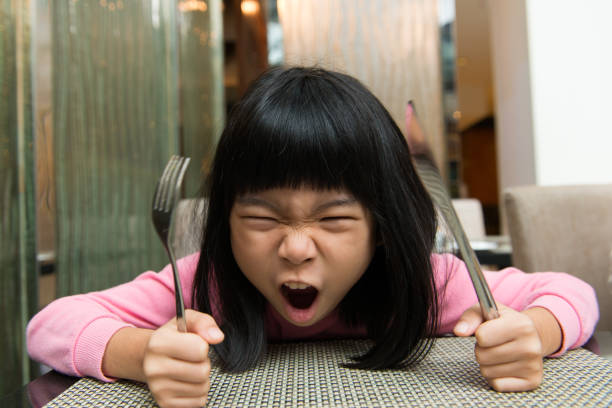 Hungry girl waiting for food Little Asian girl waiting at table screaming for food impatient stock pictures, royalty-free photos & images