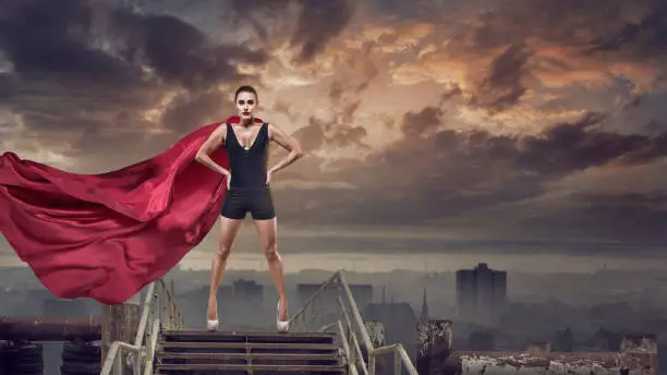 Portrait of young hero woman with super person red cape