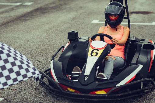 Mid adult woman go-Karts. Sitting in the car and driving race on driveway.