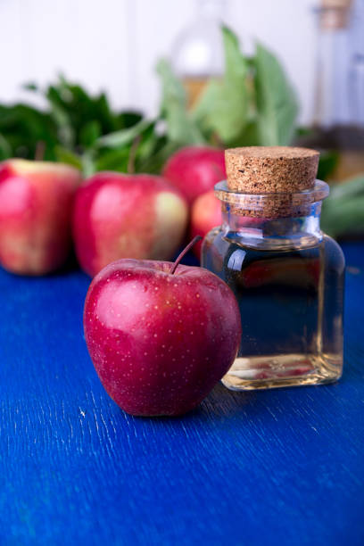 istock Apple cider vinegar. One glass bottle on blue background. Red apples. 801687116