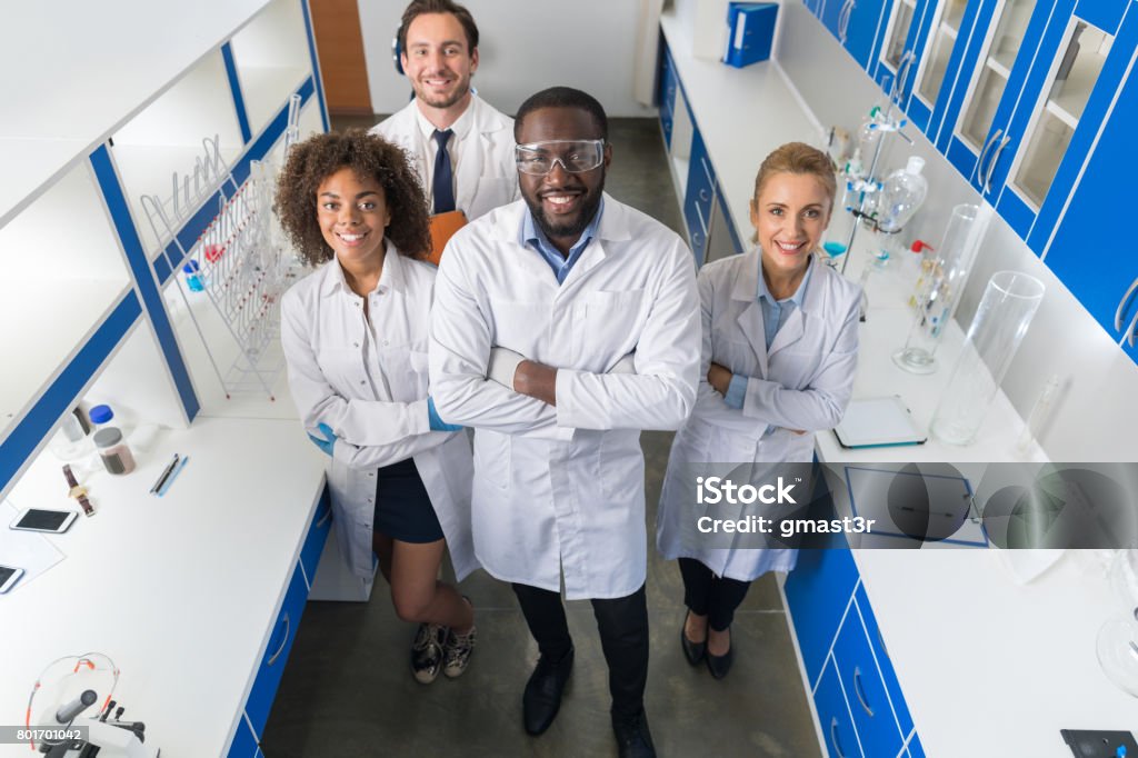 Scienziato afroamericano con gruppo di ricercatori nel laboratorio moderno Happy Smiling, mix race team di ricercatori scientifici in laboratorio - Foto stock royalty-free di Scienziato
