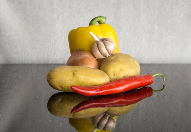 The Potato is a vegetable that is one of the main staples of the Western food world.  High in Carbohydrate, starch and low in fat.  The Potato also contains antioxidants that protect the body.  Here we also see a raw Onion, Garlic Clove and Chili Peppers.