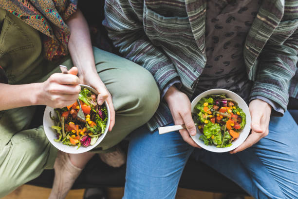 couple eating healty salad at home on the sofa - healty imagens e fotografias de stock