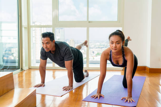 pareja adulto joven haciendo yoga en casa - stretching boyfriend indoors lifestyles fotografías e imágenes de stock