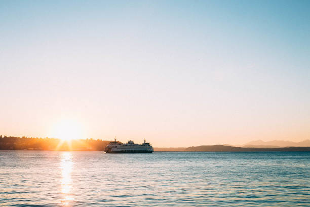 This ferry is on the Puget Sound in Seattle, Washington. The sun is setting behind the island and the ferry boat.