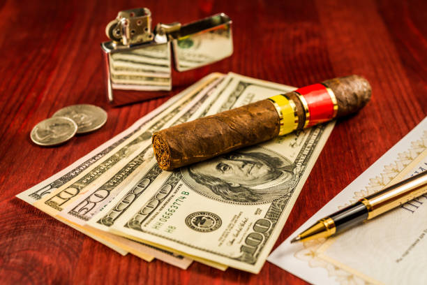 istock Cuban cigar on a several dollar bills and golden pen with bank check 801821658