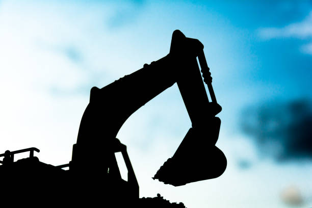 istock silhouette tracked excavator Sand and stone And sky background 801830678