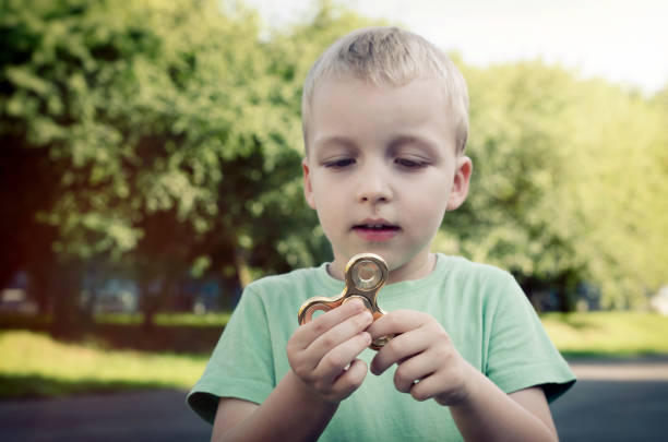 niño pequeño con un spinner de fidget al aire libre - child sensory perception expressing negativity human hand fotografías e imágenes de stock