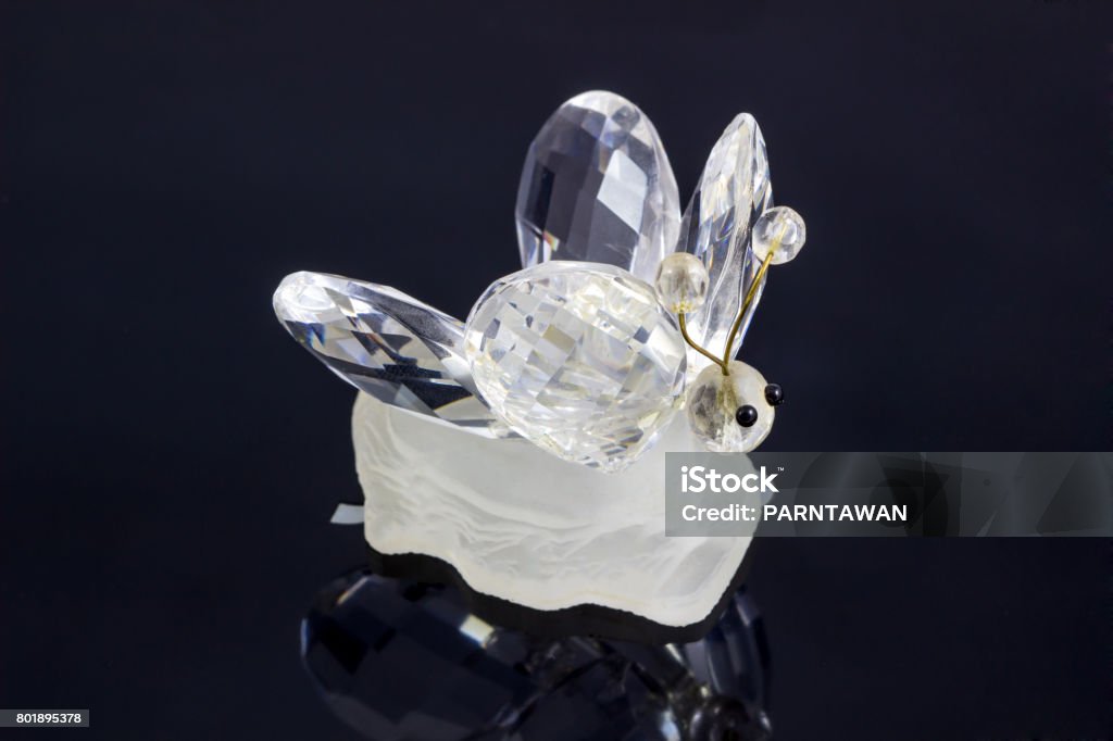 Crystal bee animal on Black Satin Background. / souvenir in the form of crystal  bee with Reflection from a metal ridge surface is visible. Amber Stock Photo