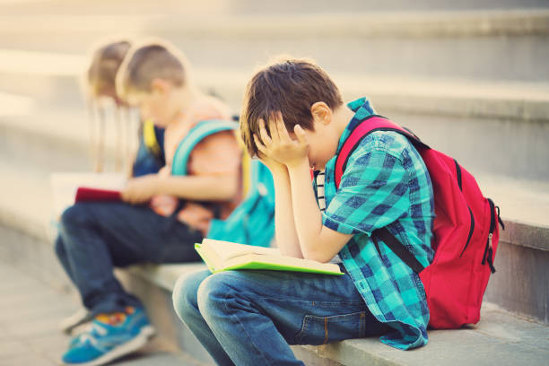 bambini con zaini seduti sulle scale vicino a scuola - emotional stress looking group of people clothing foto e immagini stock