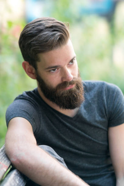 istock Thoughtful bearded guy sitting on a bench in park 801932066