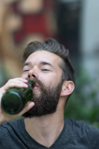 istock Handsome hipster guy with a bottle of beer in park 801939132