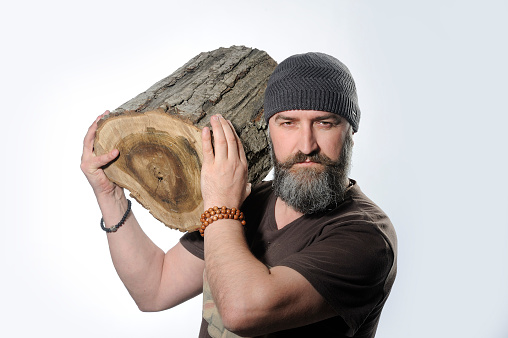 Bearded man holds a log in his hand, white background. He is strong and man. Nikon D700 Camera