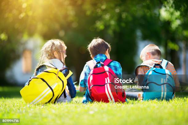 Children With Rucksacks Standing In The Park Near School Stock Photo - Download Image Now