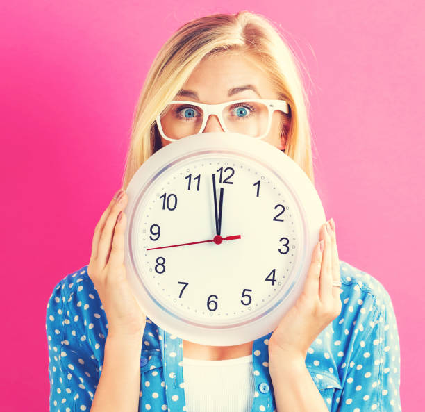 istock Woman holding clock showing nearly 12 802004668