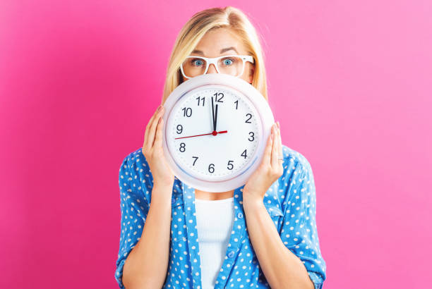 istock Woman holding clock showing nearly 12 802004678