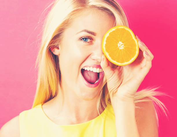 istock Happy young woman holding oranges halves 802004688