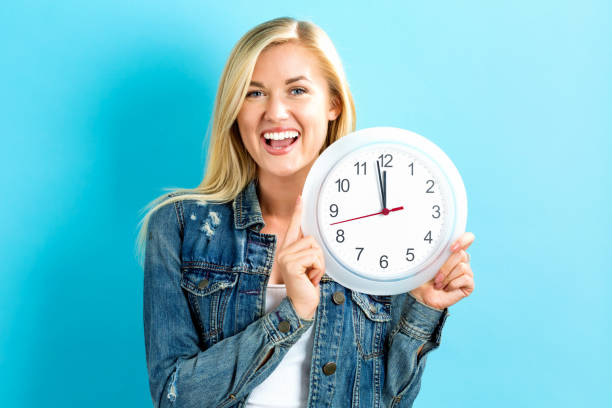 istock Woman holding clock showing nearly 12 802004730