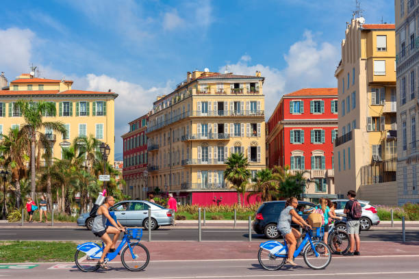 People on bicycles and colorful buildings of Nice on background. stock photo
